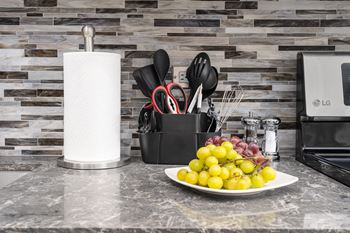 A kitchen counter with a plate of fruit and a roll of paper towels